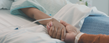 Banner image showing Two hands holding on top of a hospital bed