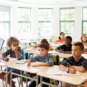 students sitting at a desk in their classroom