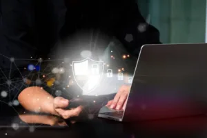 Cybersecurity protection concept showing a digital shield and network security icons over a laptop and a mobile device.